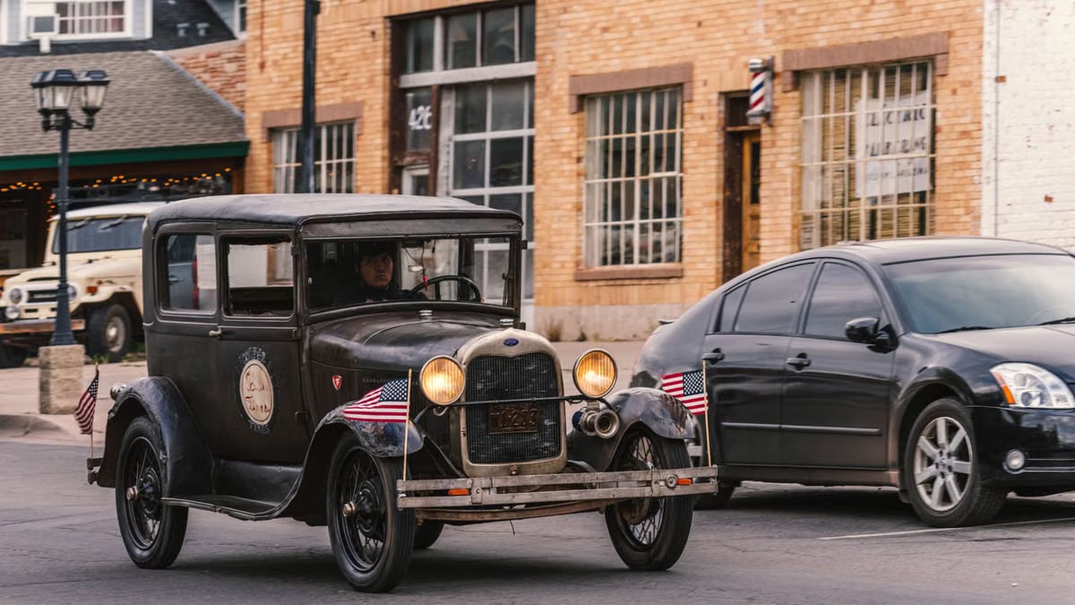 Vintage Ford with American flags driving on historic Route 66 in Williams, Arizona.